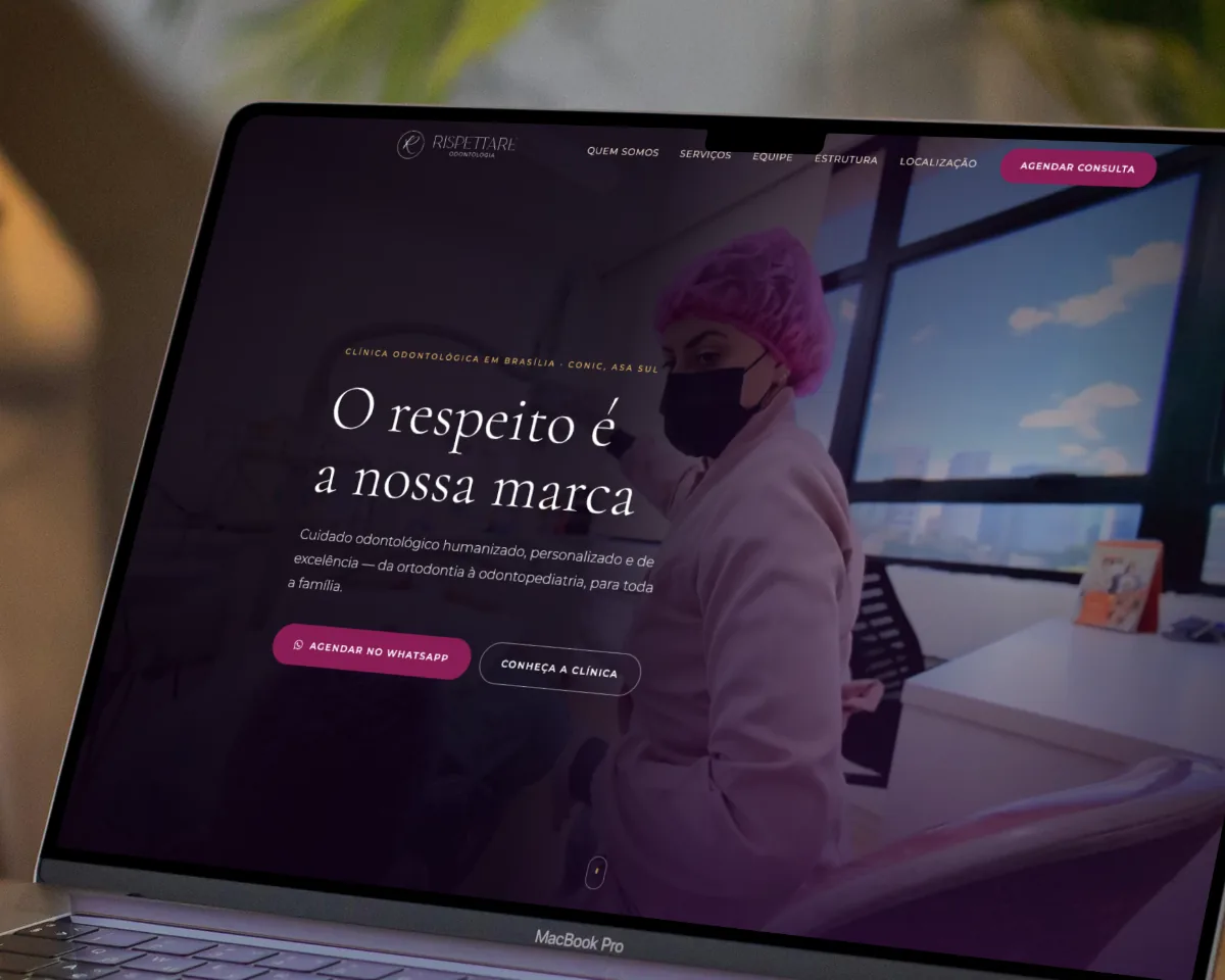 Cartões de visita da Clínica Rispettare sobre uma mesa de madeira, ao lado do site da clínica aberto num notebook.